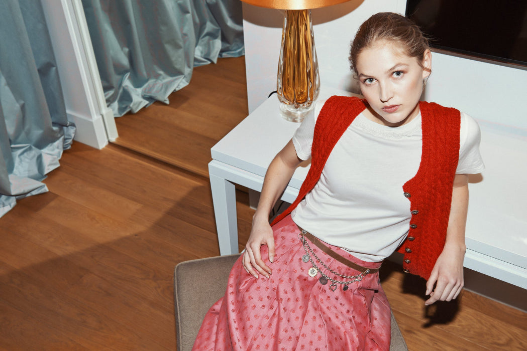 Trachtenrock Susi in der Farbe Rosa-Rot kombiniert mit roter Strickweste und Charivari Gürtel. 